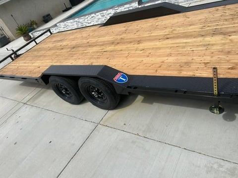 Black enclosed utility trailer with wood deck and dual wheels parked on concrete driveway